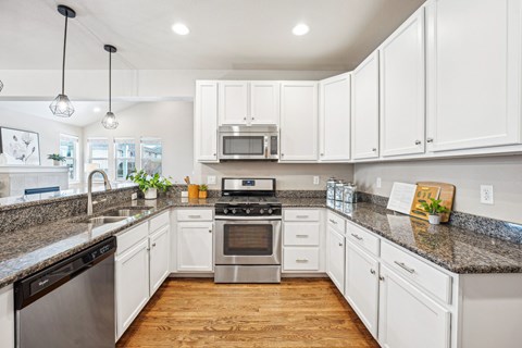 A kitchen with white cabinets and a granite countertop.