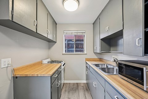 A kitchen with a wooden counter top and stainless steel appliances.