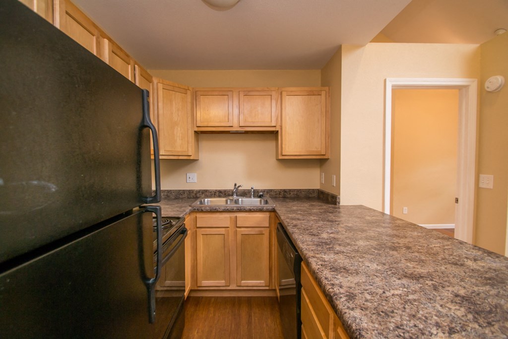 a kitchen with granite counter tops and a black refrigerator