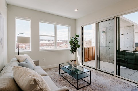 A living room with a glass coffee table and a view of the outside.