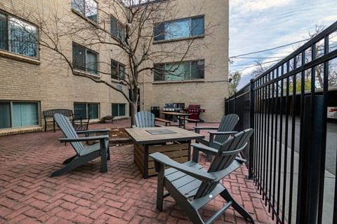 A patio with a table and chairs is surrounded by a black fence.