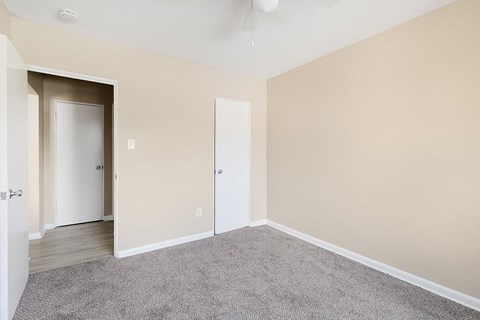 A room with a carpeted floor and two doors.