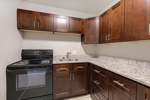A kitchen with a black stove top oven and brown cabinets.