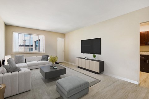 A modern living room with a grey sofa, a black television, and a grey coffee table.