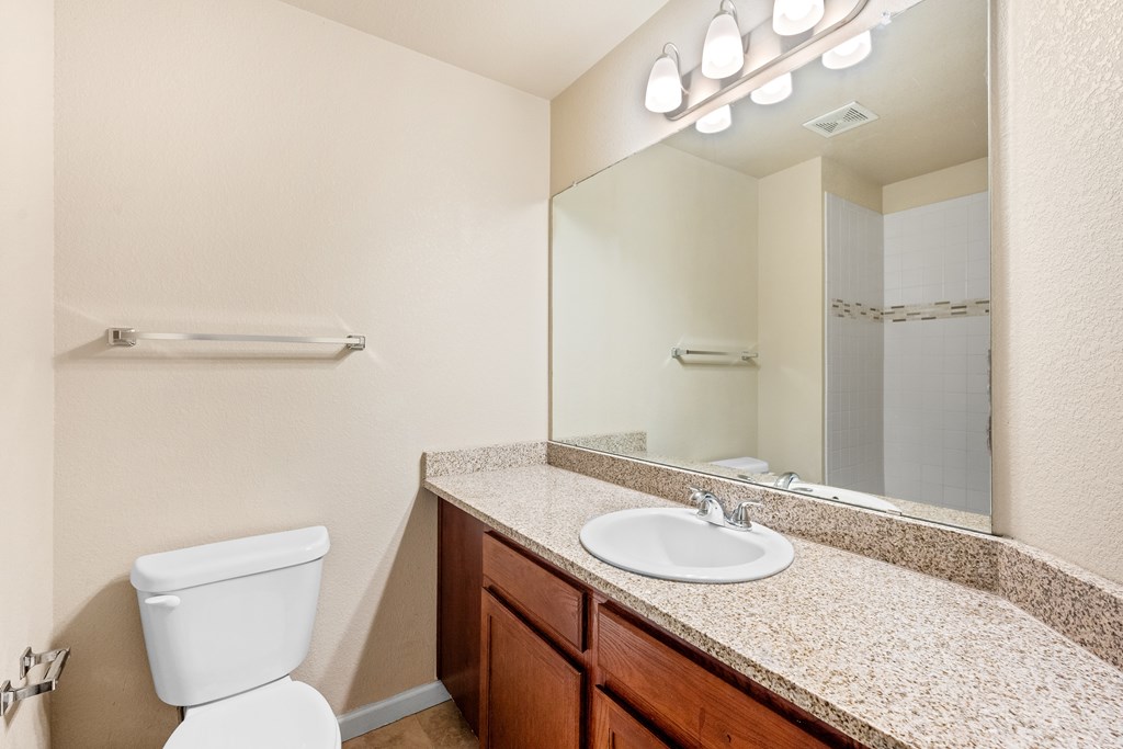 A bathroom with a toilet, sink, and mirror.
