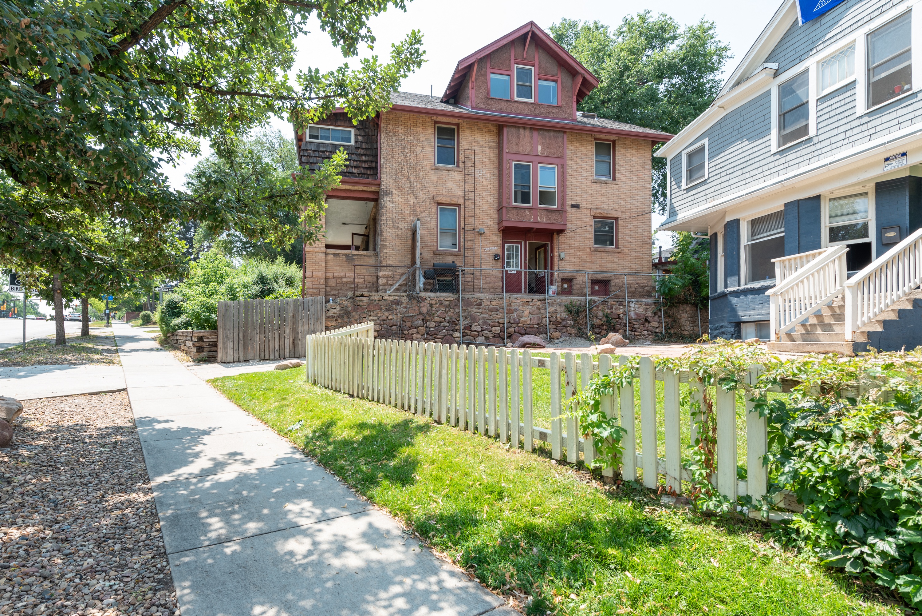 an old brick house with a white fence in front of it