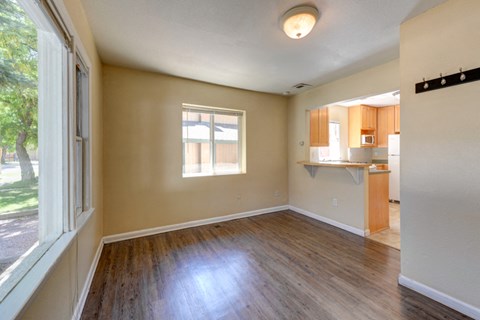 an empty living room and kitchen with wood flooring and a window
