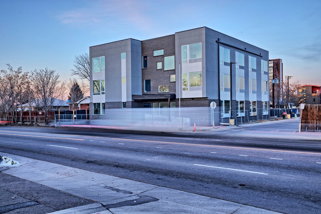 A modern building with a glass facade is situated on a street corner.