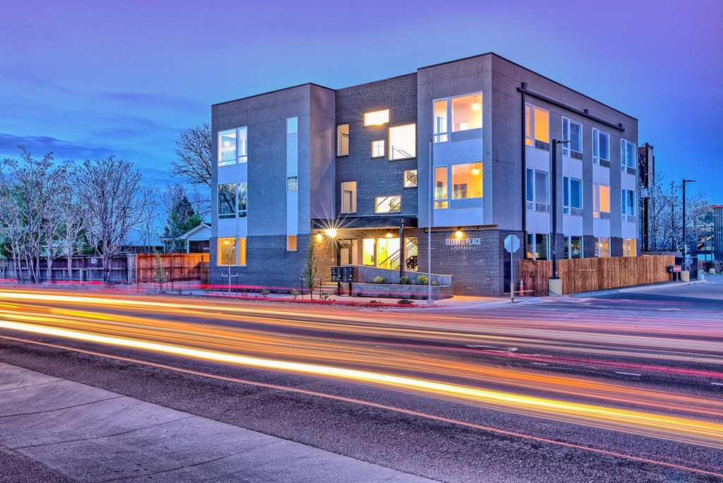 A modern building with a lot of windows and a long exposure of the street in front.