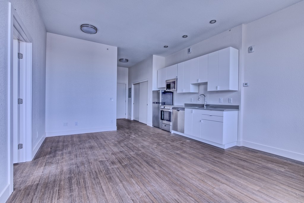A kitchen with white cabinets and a wooden floor.
