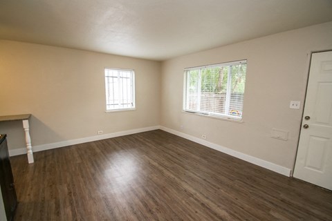 an empty living room with wooden floors and a window