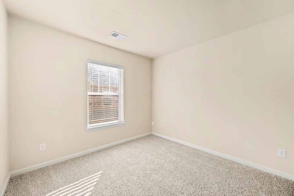 A room with a window and carpeted floor.