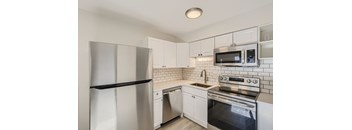 A kitchen with white cabinets and a stainless steel refrigerator.