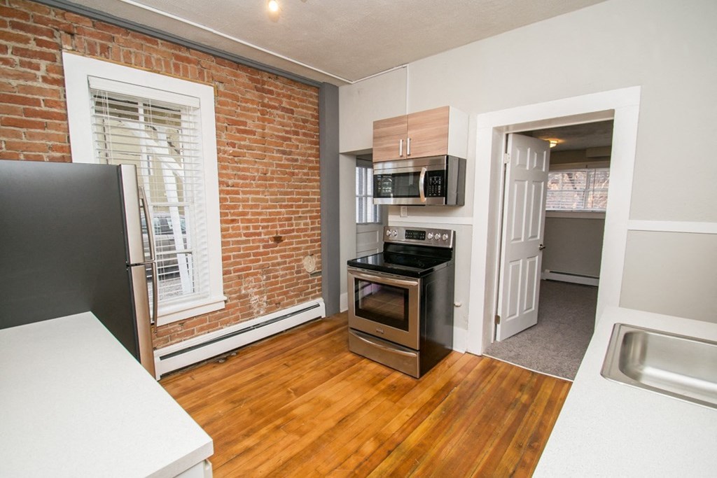 an empty kitchen with a brick wall and a window
