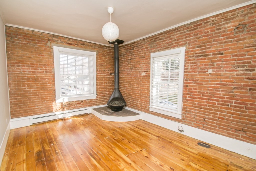 an empty living room with a brick wall and wood floors