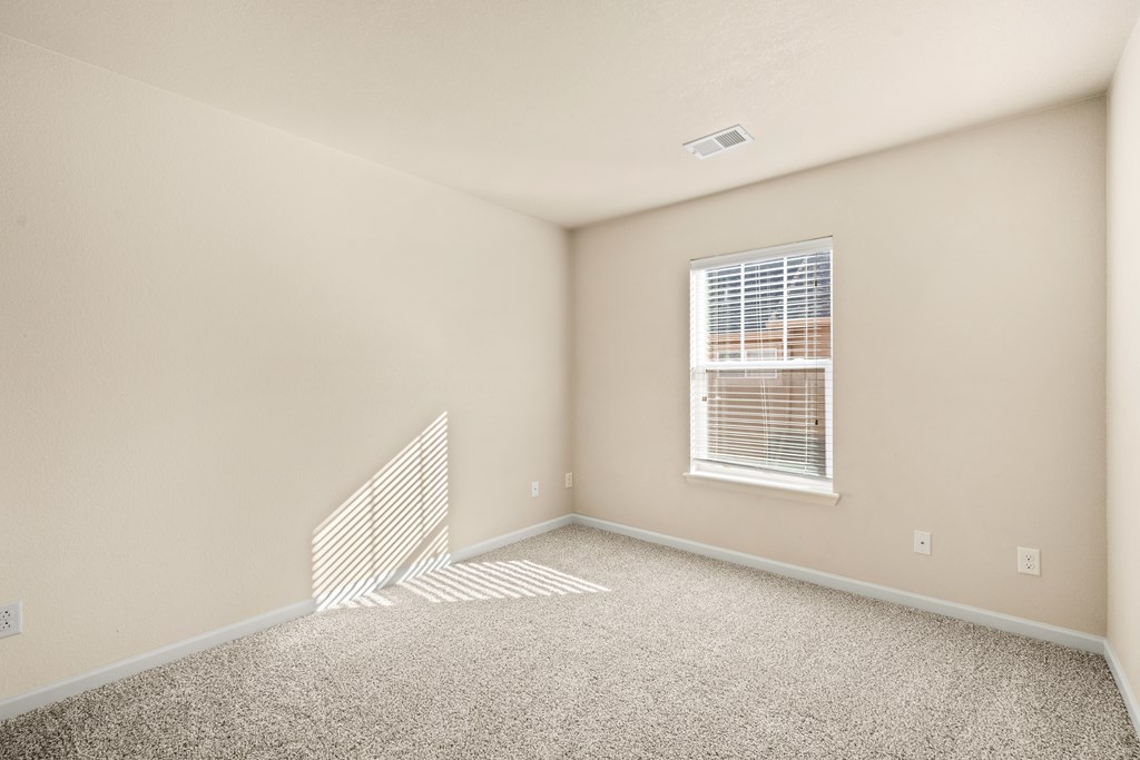 A room with a window and a carpet on the floor.
