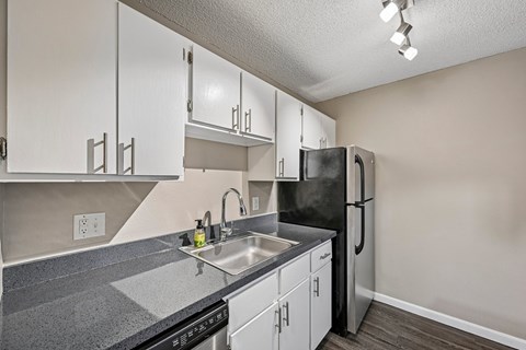 A kitchen with a black refrigerator and white cabinets.