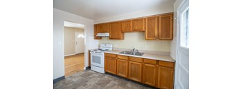 A kitchen with wooden cabinets and a white stove top oven.