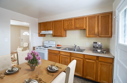 A kitchen with wooden cabinets and a dining table set for two.