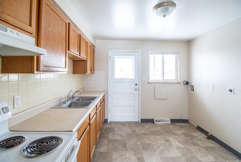 A kitchen with a white stove top oven and wooden cabinets.