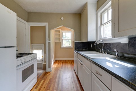 a kitchen with white cabinets and a sink and a window