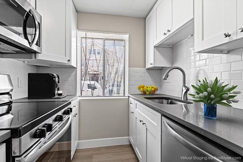 A modern kitchen with white cabinets and stainless steel appliances.