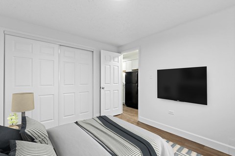 A black screen is mounted on a white wall above a bed.