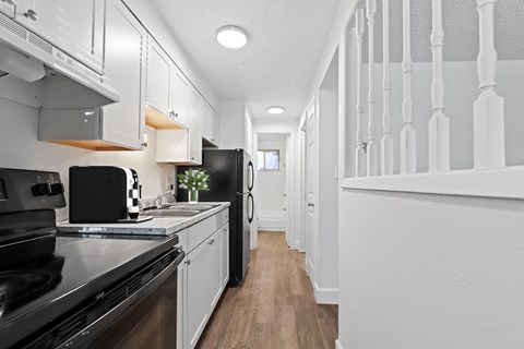 A modern kitchen with black appliances and white cabinets.