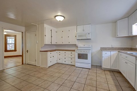 A kitchen with white cabinets and appliances.