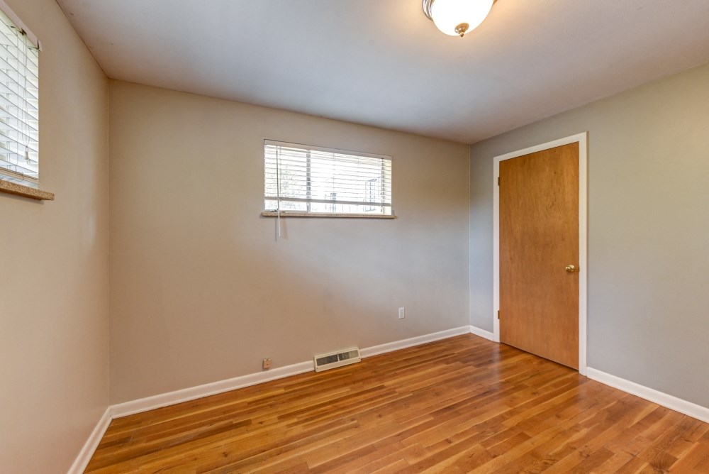 an empty living room with wooden floors and a wooden door