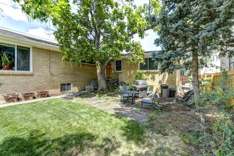 a backyard with a table and chairs in front of a house