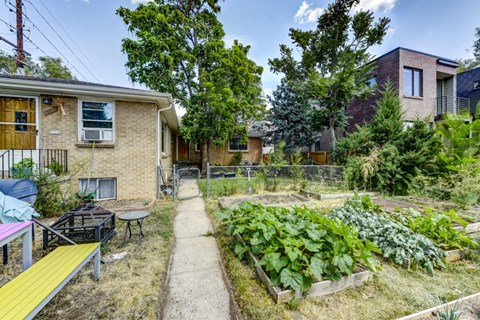 the backyard of a house with a garden and a sidewalk
