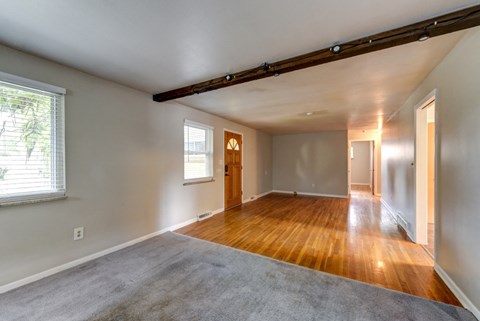 an empty living room with hard wood floors and a window