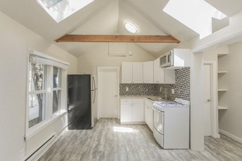 A kitchen with a black refrigerator and white cabinets.