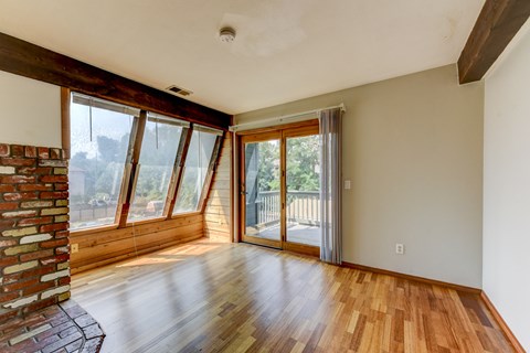 A room with wooden floors and a brick column on the left side.