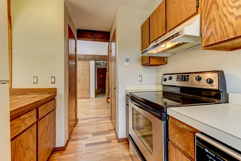 A kitchen with wooden cabinets and a stove top oven.