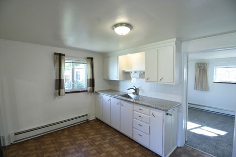A kitchen with white cabinets and a granite countertop.
