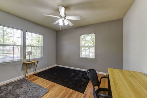 A room with a ceiling fan and a table with a chair.