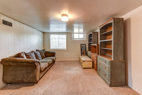 A living room with a brown couch and a window.