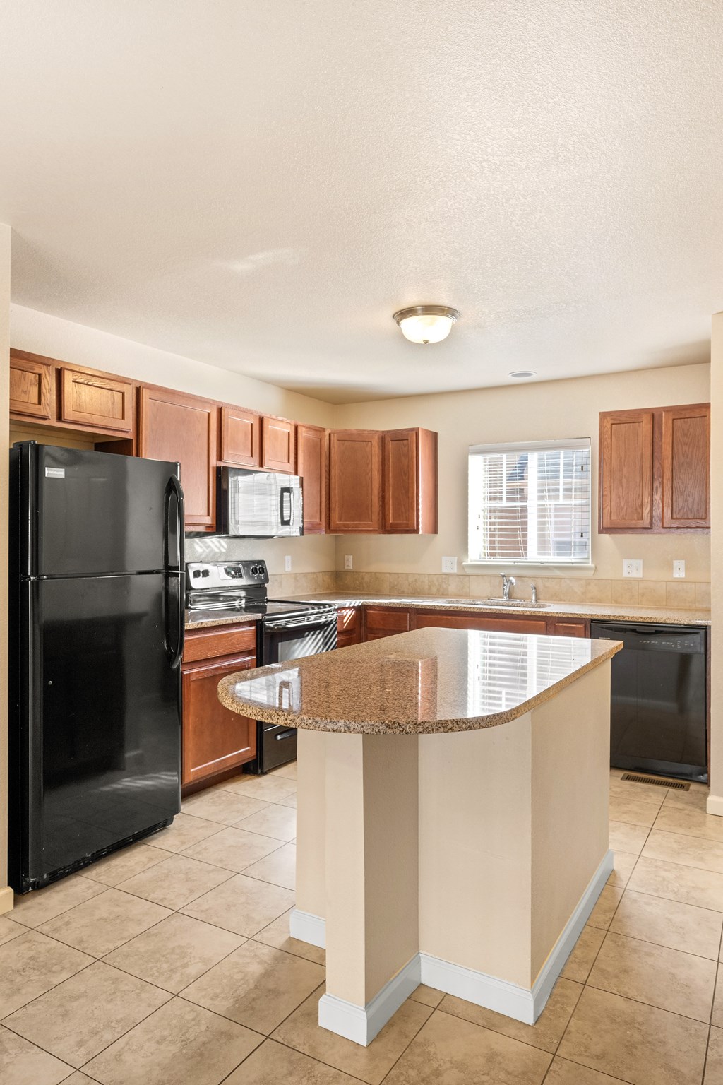 A kitchen with a black refrigerator, microwave, and dishwasher.