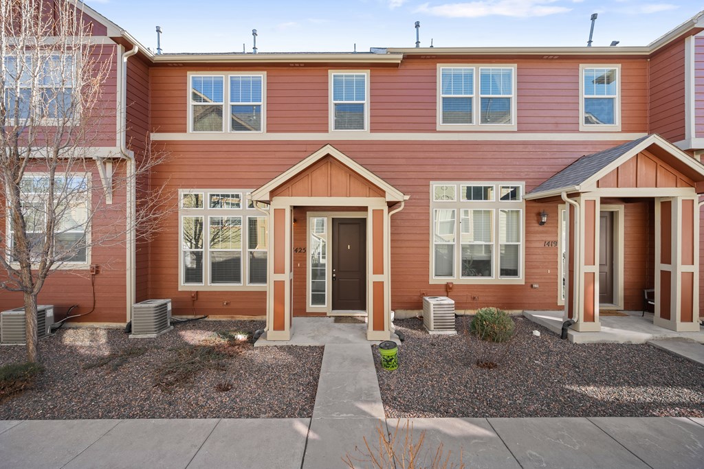 A red two-story house with a front yard and a driveway.