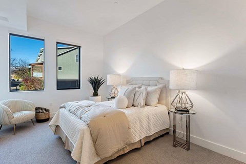 A bedroom with a large bed and a chair.