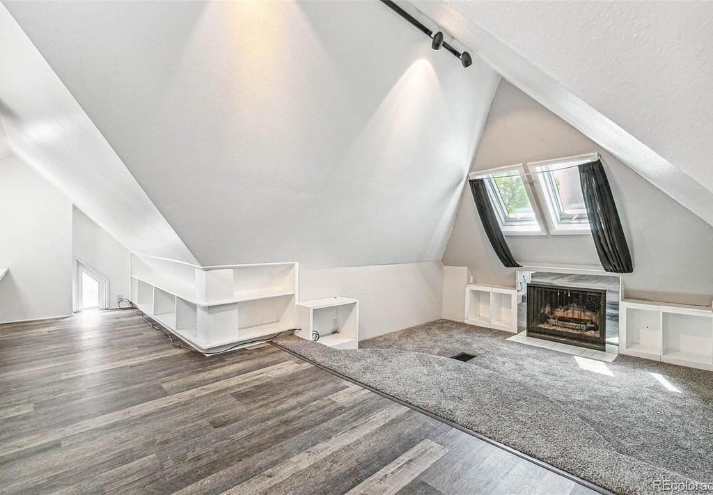 A spacious attic room with a fireplace and wooden flooring.