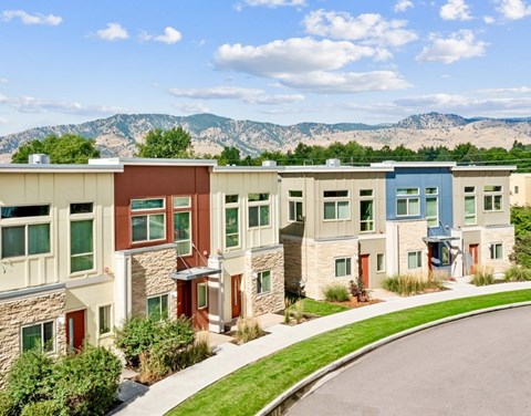A row of modern townhouses with a mountain range in the background.