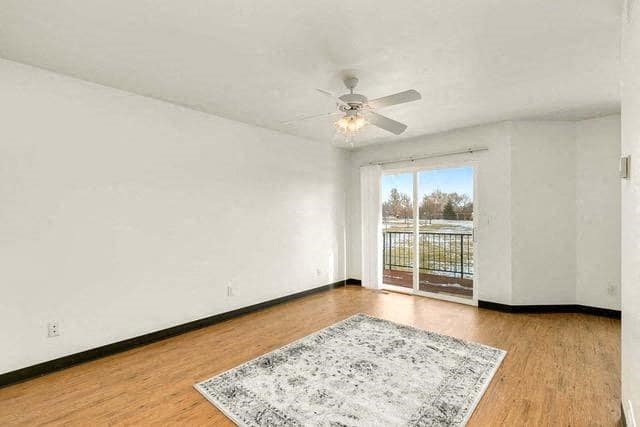 an empty living room with a ceiling fan and a window