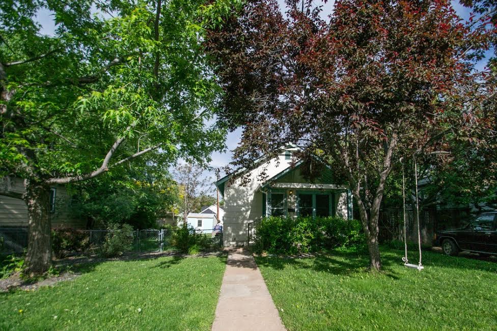 a sidewalk in front of a house with trees