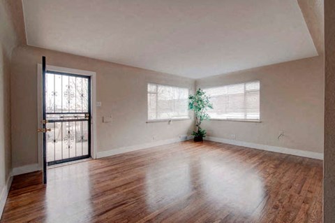 an empty living room with wood floors and a door to a balcony