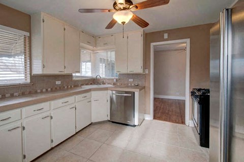 a large kitchen with white cabinets and a ceiling fan