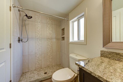 A bathroom with a toilet, a shower, and a window.