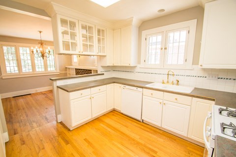 A kitchen with white cabinets and a wooden floor.